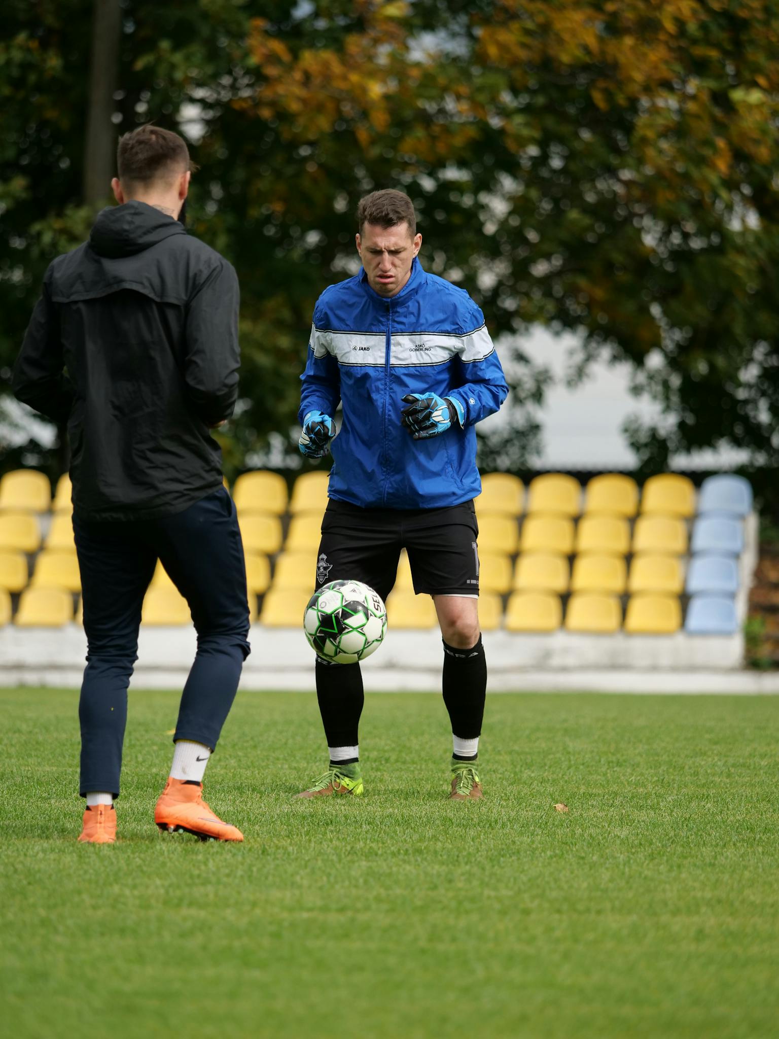 Two men practicing football drills on a green field during a training session.